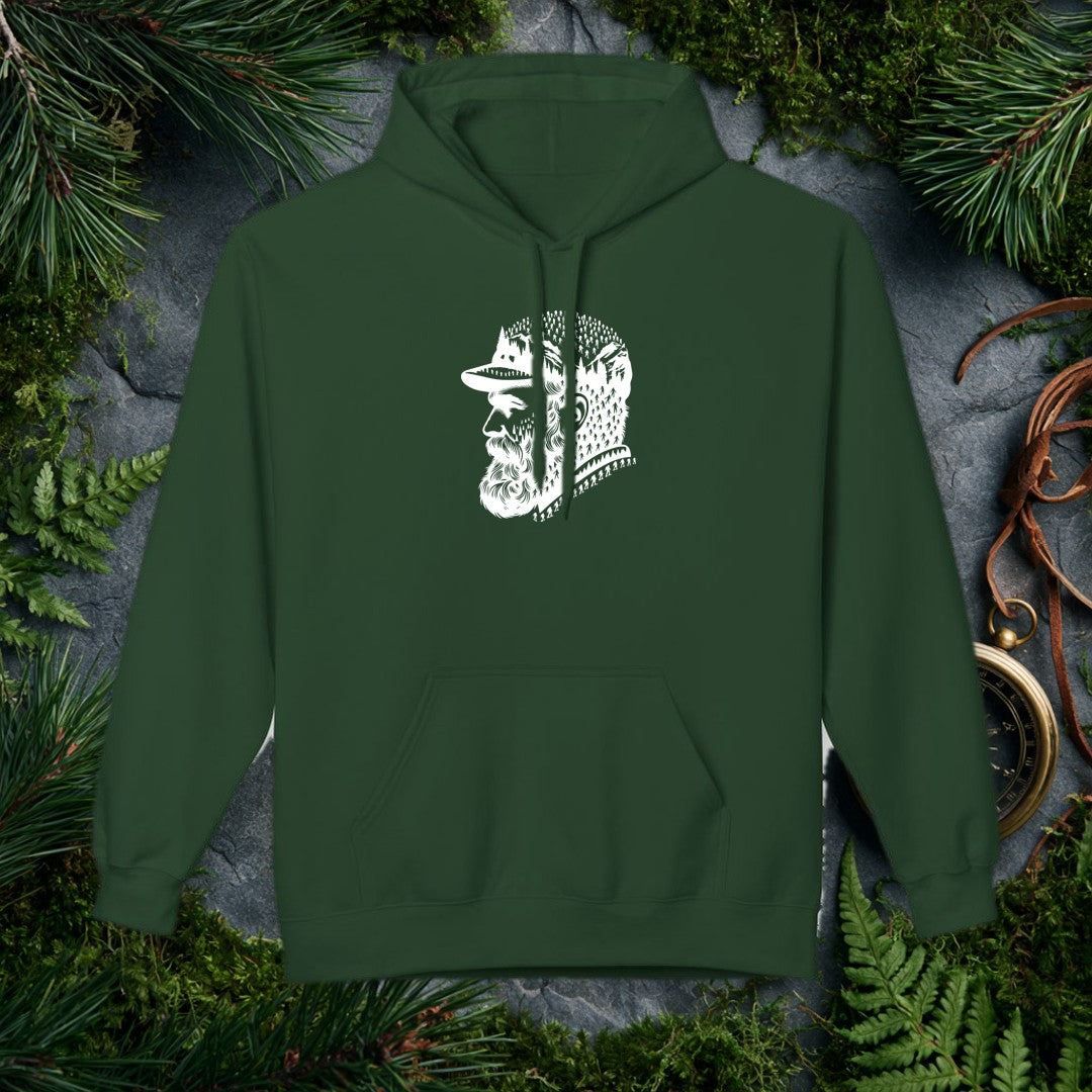 A bearded man in a trail cap looks west while pine forests, jagged peaks, and a parade of hikers — and a few unmistakable Bigfoot silhouettes — fill the…