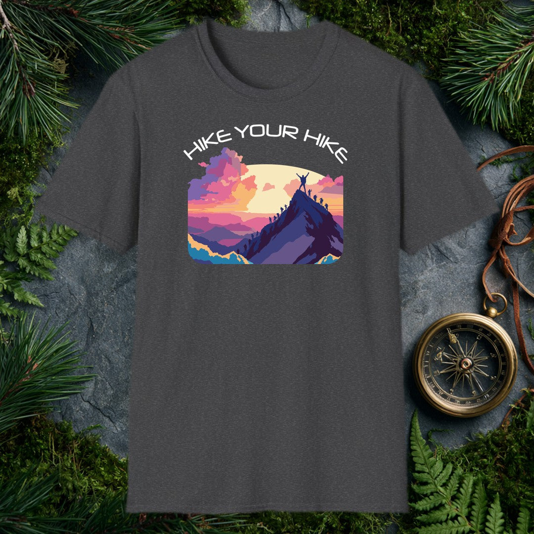 A line of silhouetted hikers winds up a sharp ridge toward the summit, where one climber stands with arms raised against a wide golden sun and a sky of rose…
