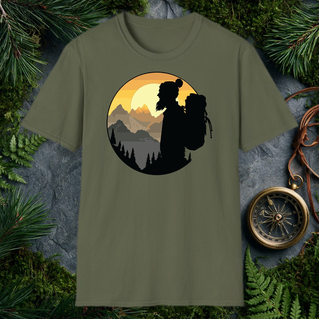 A silhouetted hiker — wool pom hat, long hair, full pack on her back — faces a layered mountain range as the sun crests behind jagged peaks above a pine-lined…