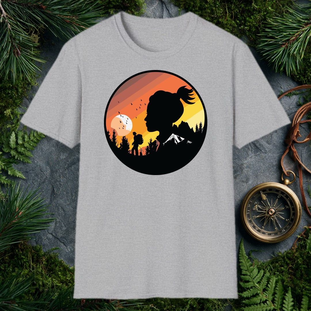 A woman's silhouette faces the horizon while a lone backpacker picks a trail through pine shadows beneath a striped sunset sky — birds lifting off a wide…