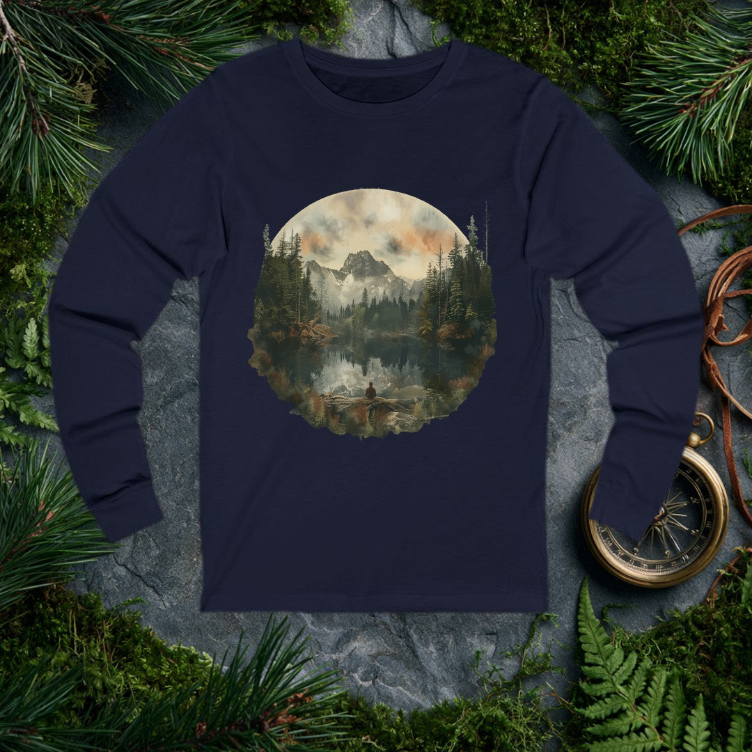 A lone figure sits on a fallen log at the edge of a still alpine lake, watching jagged snow-capped peaks and a stand of dark pines mirror themselves perfectly…