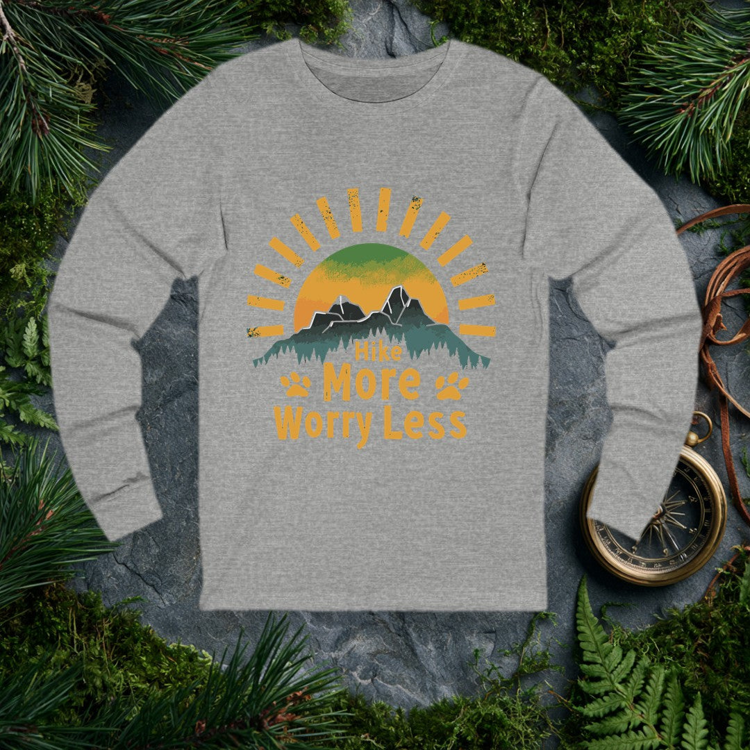 A half-sun rises behind two jagged mountain peaks and a ridge of dark pines, with paw prints flanking the words Hike More Worry Less — for the hiker who brings…