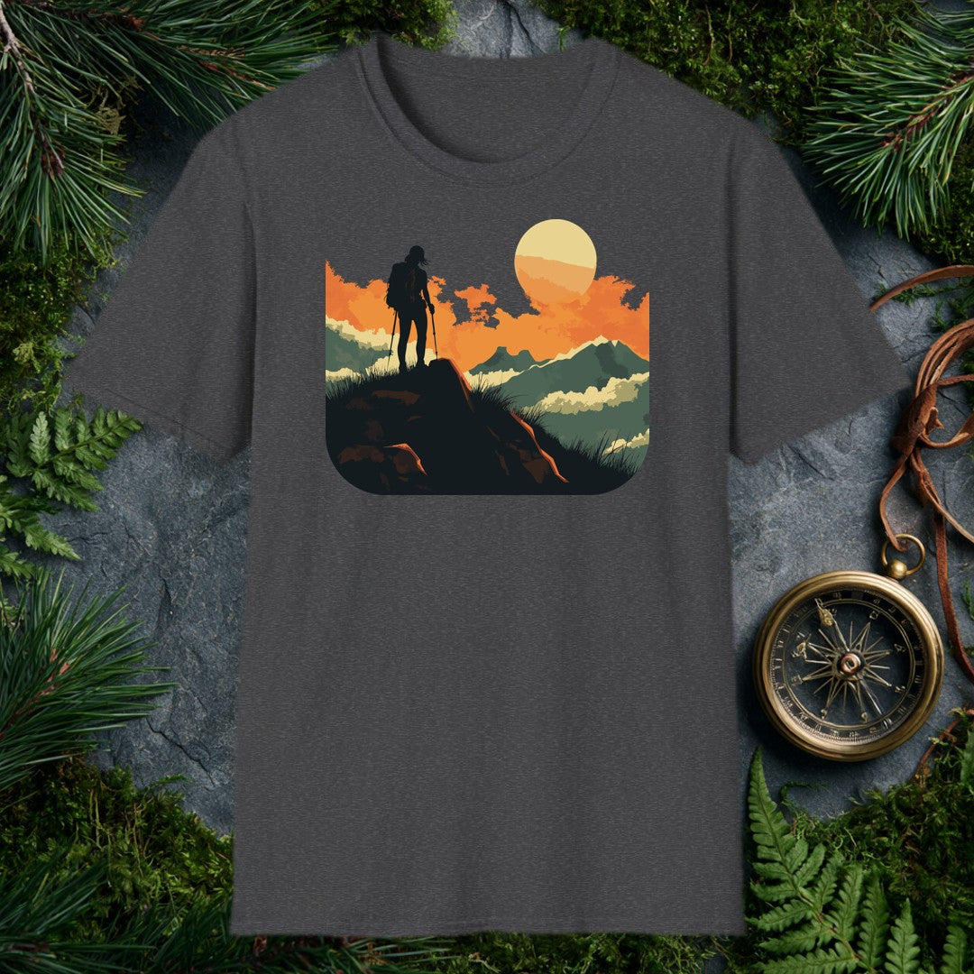 silhouette of a female hiker with backpack and trekking poles standing on a rock at sunset with layered mountains behind
